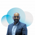 A man is smiling in a suit in front of the cloud from the Digital Cloud UK logo