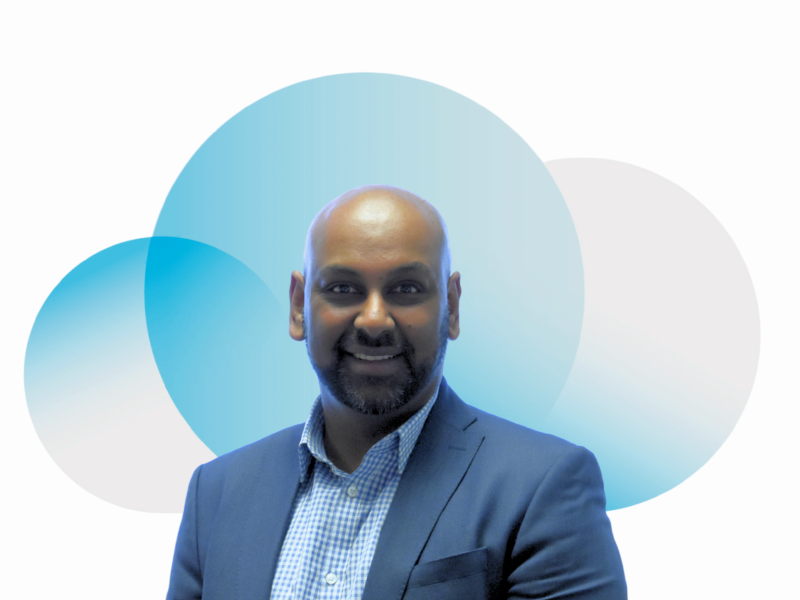 A man is smiling in a suit in front of the cloud from the Digital Cloud UK logo