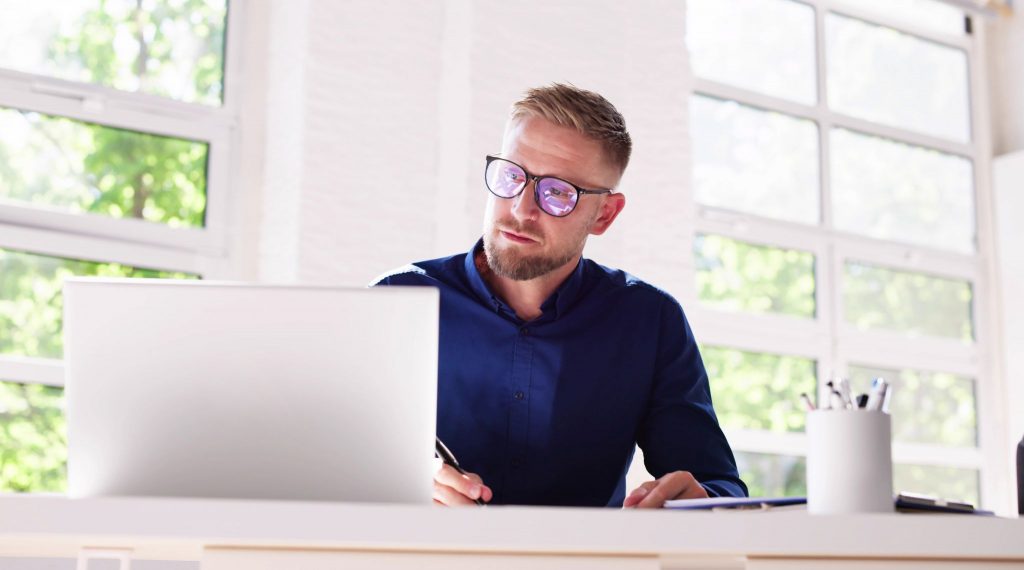 A man is working on a laptop, he is completing a course from the new government AI training scheme.